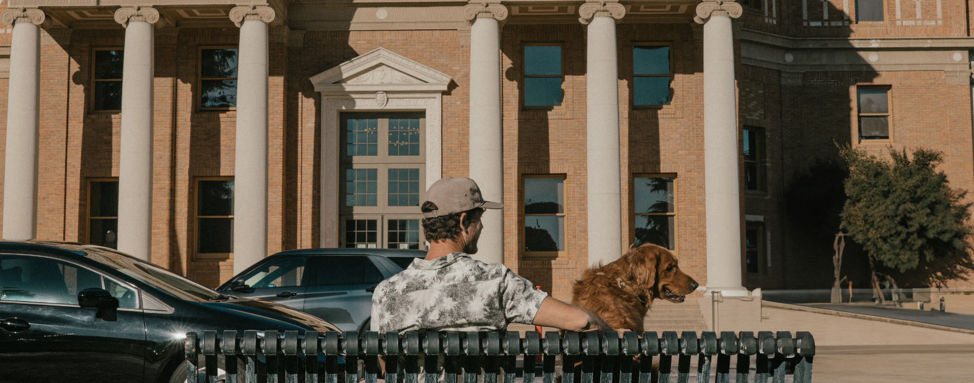 A dog and a person sitting on a bench outside Atascadero's Historic City Hall