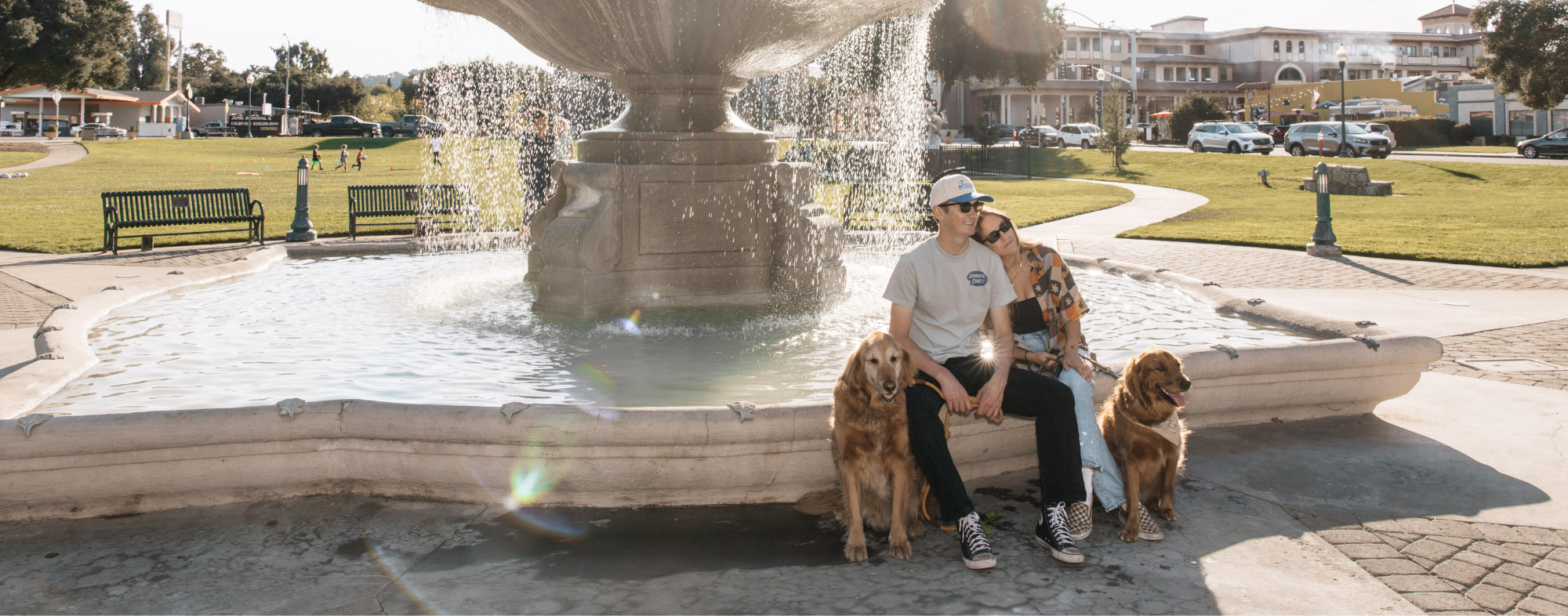 Two dogs and their humans sitting by the fountain in Atascadero's Sunken Gardens