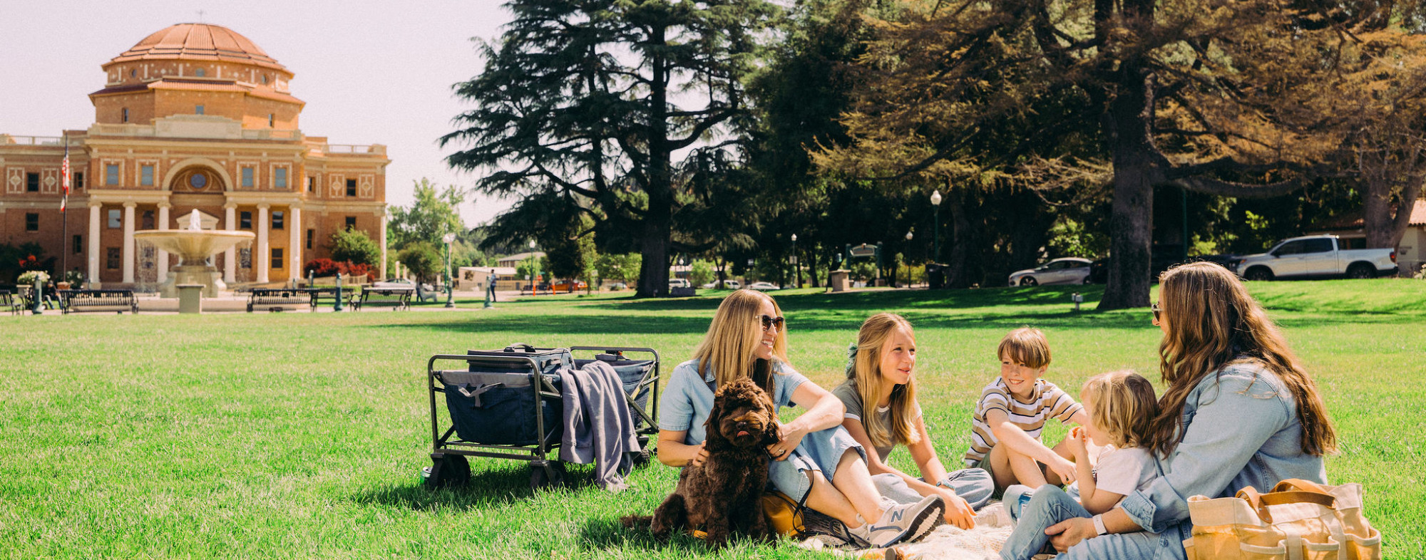 A family and a dog sitting on the grass in Atascadero's Sunken Gardens